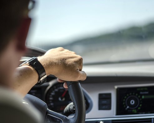 Man Driving Car with One Hand on Steering Wheel